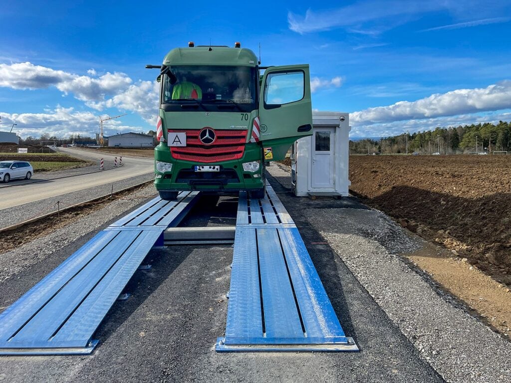 Vrachtwagen op blauwgelakte mobiele stalen weegschalen HE-TS op bouwplaats