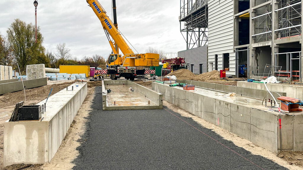 Gele mobiele kraan achter betonnen fundering op geprepareerde grindlaag